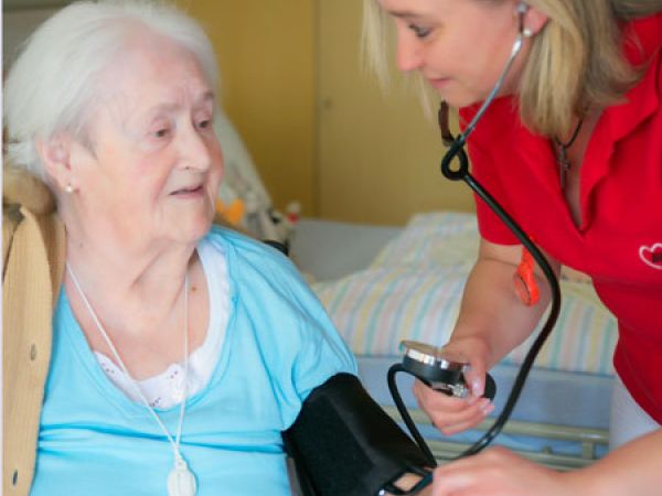 Pflegerin misst bei Seniorin den Blutdruck