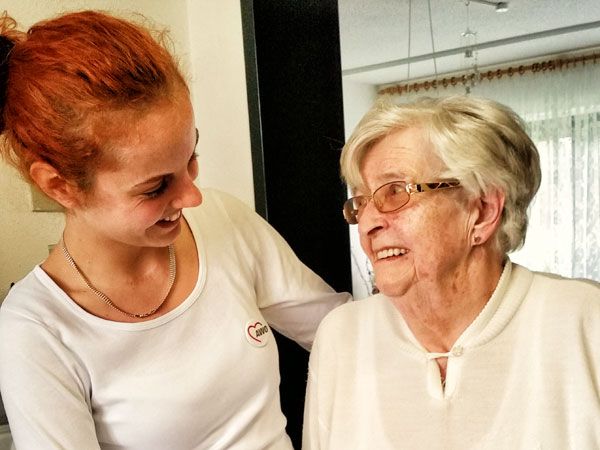 Pflegerin und Seniorin lächeln