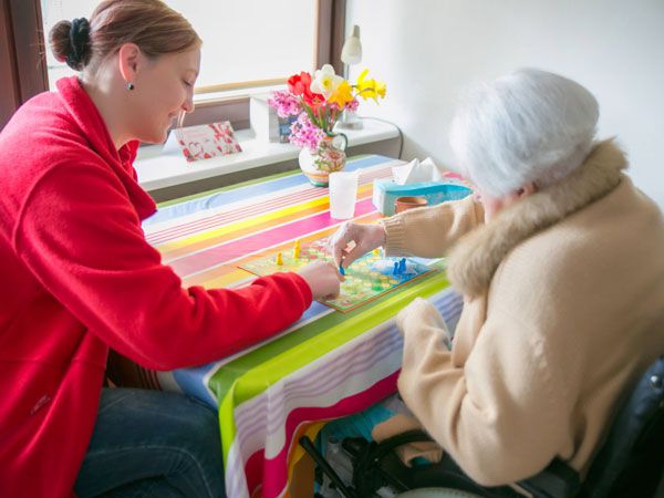 Pflegerin spielt mit Seniorin